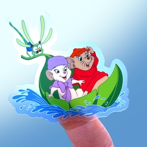 May include: A sticker featuring two cartoon mice in a green leaf boat, with a dragonfly flying above them. The mice are wearing hats and are smiling. The boat is floating on blue water.