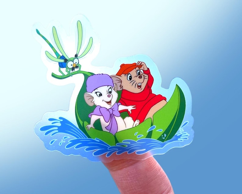 May include: A sticker featuring two cartoon mice in a green leaf boat, with a dragonfly flying above them. The mice are wearing hats and are smiling. The boat is floating on blue water.
