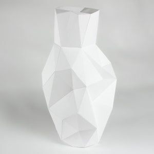 Peut inclure: Un vase en céramique blanche avec un design géométrique. Le vase est composé de nombreux petits triangles qui créent un look unique et moderne.