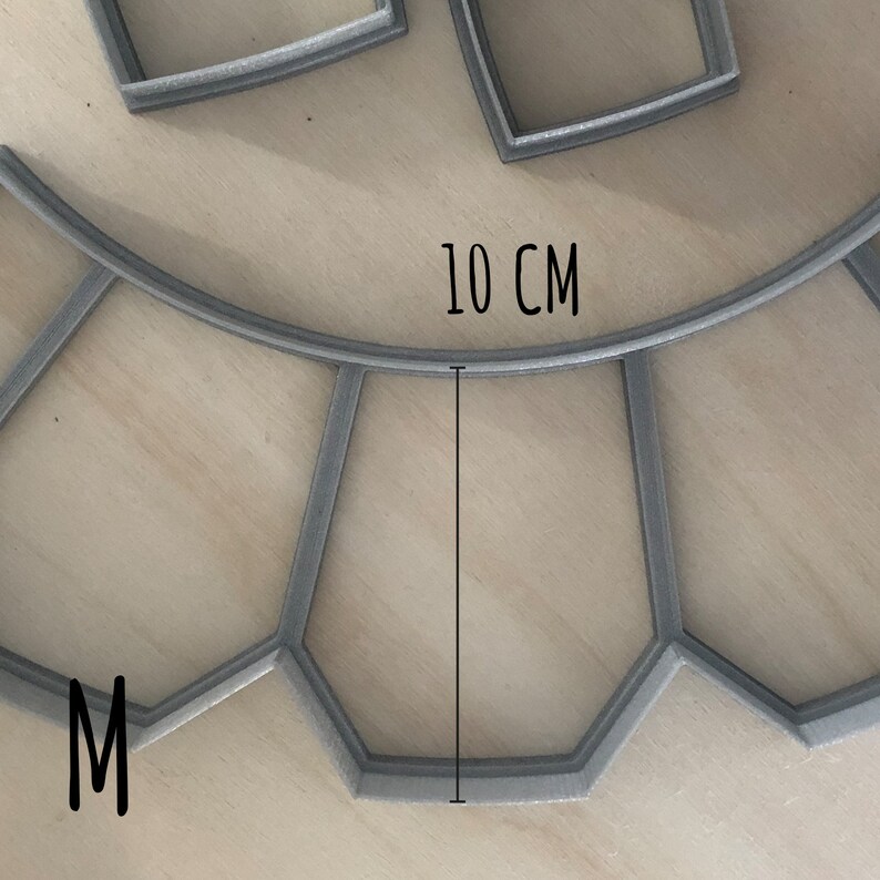 May include: A gray metal mold with a 10 cm diameter, shaped like a circle with a section cut out. The mold is labeled with the letter "M".