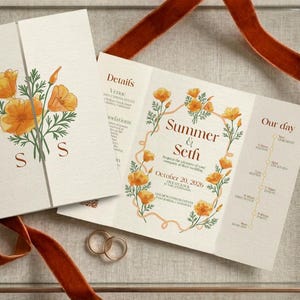May include: Wedding invitation suite featuring a floral design with orange poppies and green foliage. The invitation is displayed in a glass box with a rust-colored ribbon and a sprig of flowers. Two wedding rings are also visible.