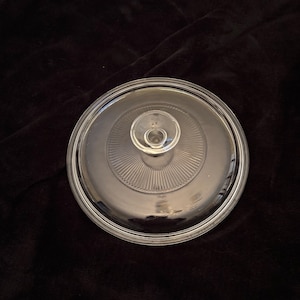 May include: Clear glass cake stand with a raised center and a fluted edge.