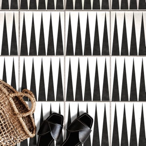 May include: Black and white geometric tile floor with a black and white pattern of triangles. Two black leather sandals are on the floor.