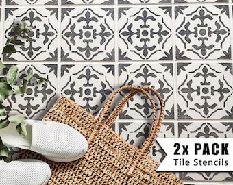 May include: Two black and white tile stencils with a decorative floral pattern. The stencils are on a white tiled floor with a woven bag and white shoes.