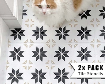May include: Two black and white tile stencils with a starburst design. The stencils are on a white floor with a cat standing on them. The text "2x PACK Tile Stencils" is in the lower right corner of the image.