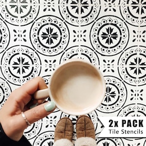 Puede incluir: Dos plantillas de azulejos en blanco y negro con un patrón geométrico. Las plantillas están sobre un suelo blanco con una taza de café y zapatillas marrones.