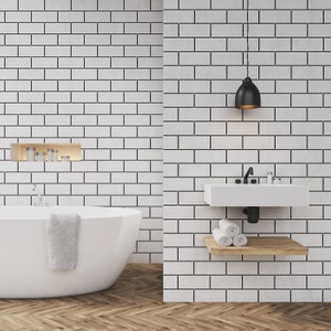 Può includere: Un bagno bianco con pareti in piastrelle bianche a metro, una vasca da bagno bianca, un lavandino bianco con un rubinetto nero e uno scaffale in legno con asciugamani bianchi. Una lampada a sospensione nera pende dal soffitto.