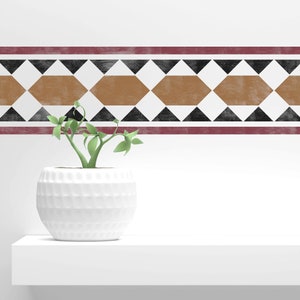 May include: A white ceramic planter with a textured surface, holding a small green plant. The planter is sitting on a white shelf with a decorative border of black and brown geometric shapes.