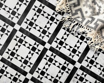 May include: Black and white geometric tile pattern with a white and gray blanket on top.