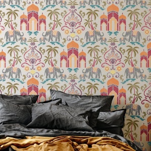 May include: A bed with a grey headboard and a gold throw blanket. The headboard features a patterned wallpaper with elephants, arches, and palm trees in shades of orange, red, yellow, and blue.