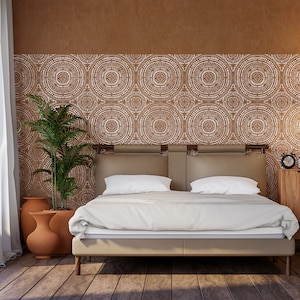 May include: A white bed with a brown headboard and a white bedspread. The headboard features a geometric pattern of circles. There are two potted plants in the room.