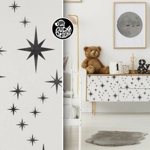 Peut inclure: Une commode blanche avec des autocollants en forme d'étoiles noires. La commode a deux tiroirs et est décorée d'une illustration de lune noire et blanche et d'un ours en peluche.