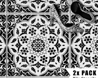 May include: Two black and white tile stencils with a floral pattern. The stencils are on a white background and are being used to create a decorative floor design. The text "2X PACK Tile Stencils" is visible in the lower right corner of the image.