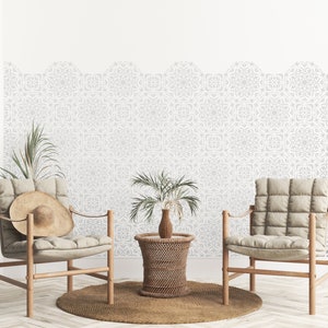 May include: Two beige chairs with wooden frames and a woven wicker side table in a living room with a white wall featuring a patterned wallpaper border.