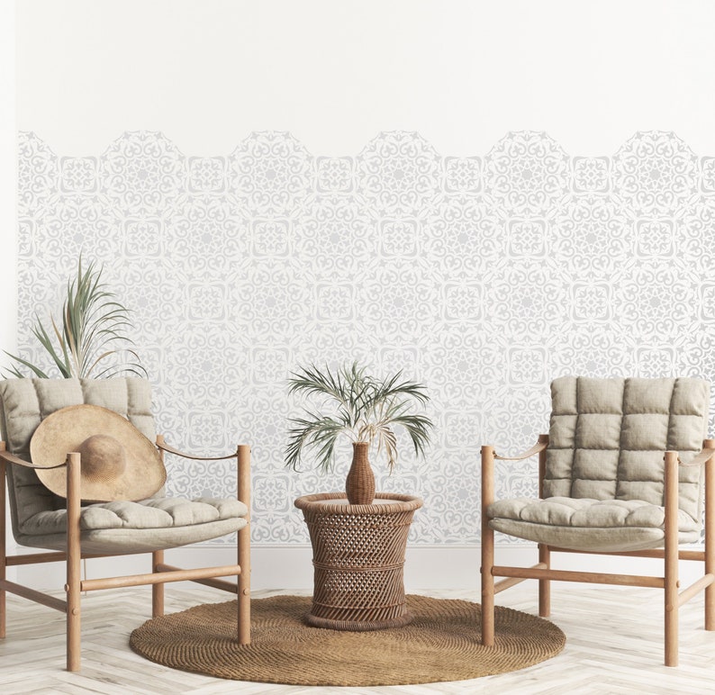 May include: Two beige chairs with wooden frames and a woven wicker side table in a living room with a white wall featuring a patterned wallpaper border.