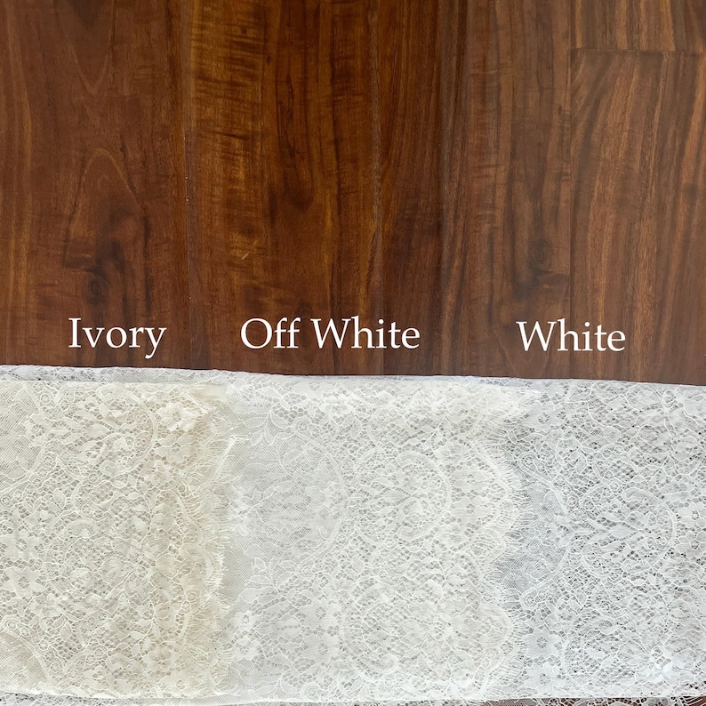 May include: A strip of lace fabric displayed in three distinct color variations labeled Ivory, Off White, and White. The lace features a detailed floral pattern with scalloped edges, showcasing the subtle differences in shade across the fabric.