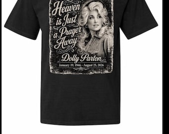 Może przedstawiać: Czarny t-shirt z krótkim rękawem z grafiką przedstawiającą Dolly Parton. Tekst brzmi Heaven is Just a Prayer Away, Dolly Parton, oraz daty January 19, 1946 - August 25, 2026. Wzór posiada postarzaną, prostokątną ramkę wokół grafiki.