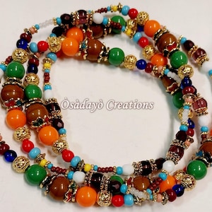 May include: Multi-colored beaded necklace with brown, orange, green, blue, red, white, and gold beads. The necklace is layered and has a variety of different sized beads. The text "Osadayó Creations" is visible in the image.