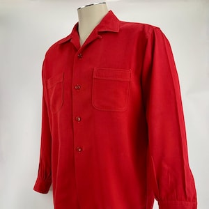 May include: A red long-sleeved button-up shirt with a collared neckline and two chest pockets.