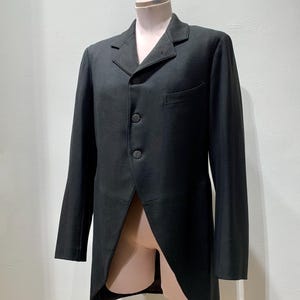 May include: A black formal tailcoat with a notched lapel, three-button closure, and a single chest pocket. The coat has long sleeves and a split back, displayed on a mannequin.