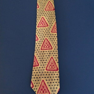 May include: A yellow tie with a repeating pattern of red triangles. The triangles have a black outline and a geometric design inside.
