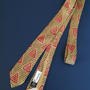 May include: A gold and red patterned silk tie with a black label that reads "Oak Hall" and "All Silk" in white text.