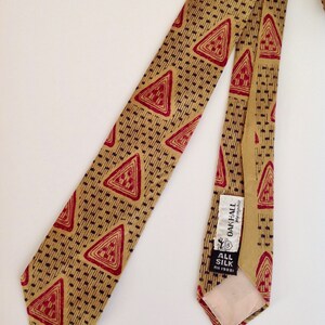 May include: A gold and red patterned silk tie with a label that reads "Oak Hall Memphis" and "All Silk" in black text.
