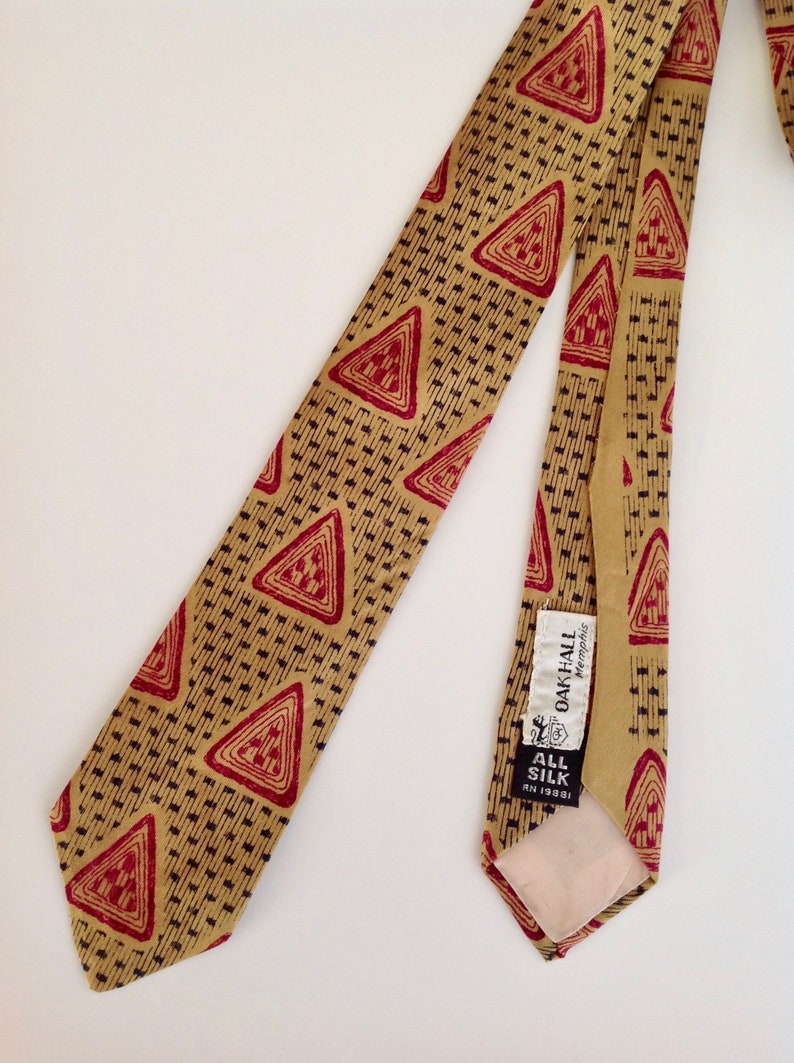 May include: A gold and red patterned silk tie with a label that reads "Oak Hall Memphis" and "All Silk" in black text.