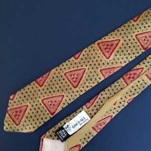May include: A gold silk tie with a red and black geometric pattern. The tie has a label that reads "Oak-All Memphis" and "All Silk Reg. 10001".