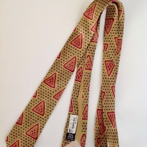 May include: A gold silk tie with a red and black geometric pattern. The tie has a label that reads "Oakhall Regimental" and "All Silk Knit 100%".
