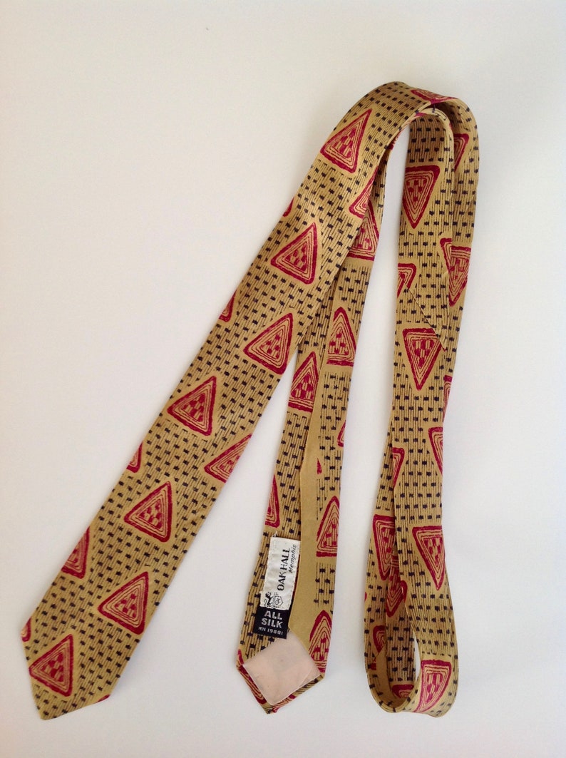 May include: A gold silk tie with a red and black geometric pattern. The tie has a label that reads "Oakhall Regimental" and "All Silk Knit 100%".
