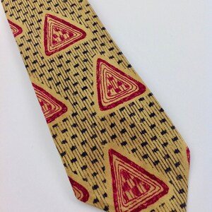 May include: A yellow tie with a geometric pattern of red triangles and black lines.
