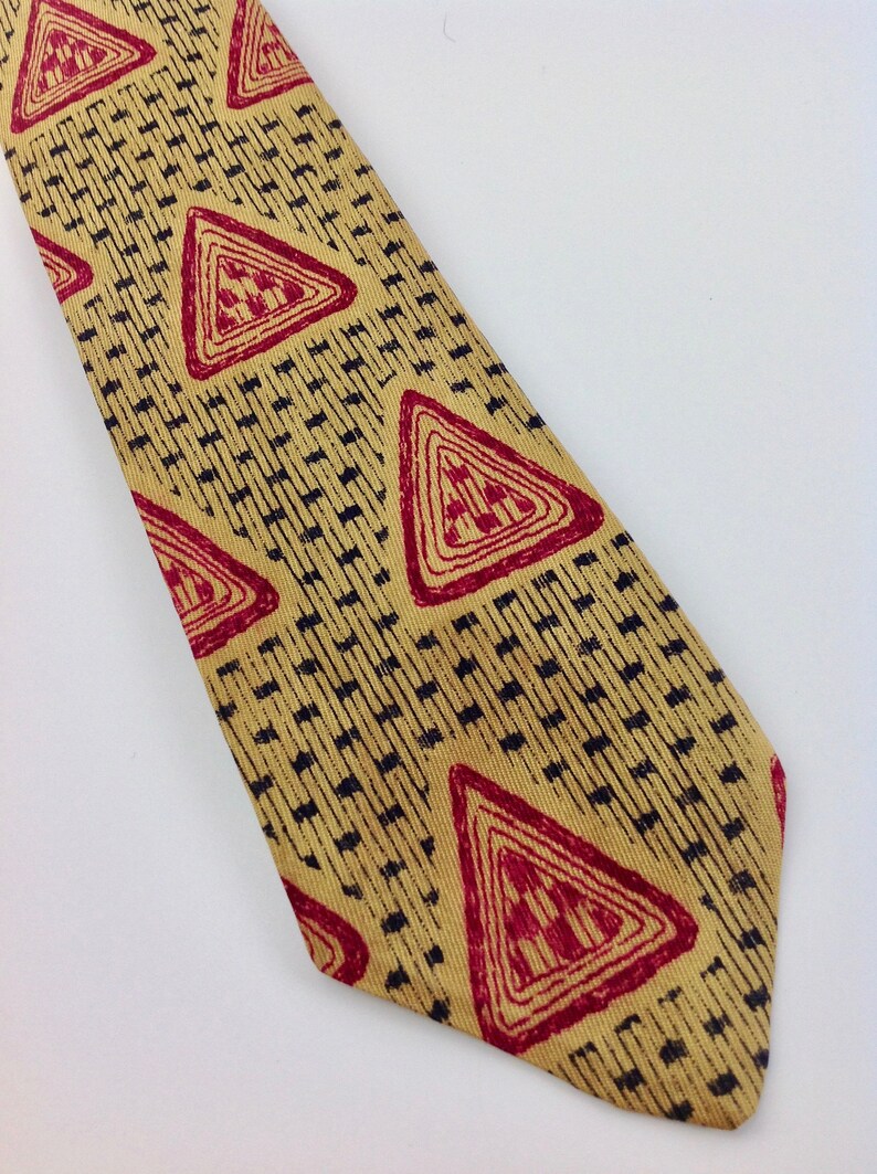May include: A yellow tie with a geometric pattern of red triangles and black lines.