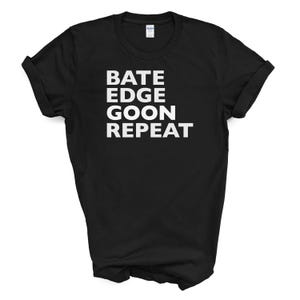 May include: Black t-shirt with the words "BATE EDGE GOON REPEAT" printed in white, centered on the front. The shirt has short sleeves and a crew neck. The fabric appears to be a soft cotton blend.