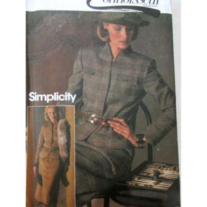 Puede incluir: Un sobre de patrón de costura Simplicity Connoisseur Collection que presenta una chaqueta de cuadros gris con cuello alto, bolsillos en el pecho con botones y cintura con cinturón. La portada muestra a una persona con la chaqueta y una falda a juego, con una imagen insertada más pequeña que muestra un traje de falda color canela con una estola de piel.