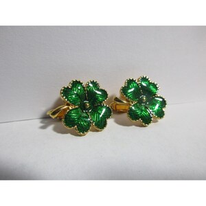 Op de afbeelding: Een paar gouden oorbellen met vierbladige klaverontwerpen in groen emaille.