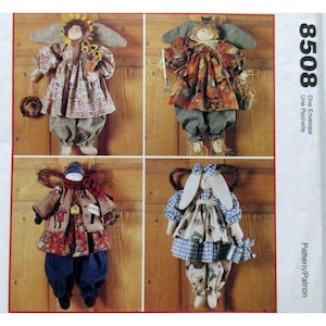 May include: Four handmade angel dolls with fabric wings and clothing. Each doll has a unique design, including a sunflower crown, a rake, a scarf, and a bunny-eared doll. The dolls are displayed against a wooden background.