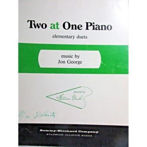 May include: A white cover for a music book titled "Two at One Piano: elementary duets" by Jon George. The cover has a green border and a green heart-shaped logo with the text "Selected by Francie Clark".