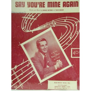 May include: A red sheet music cover with a white border and a black and white photo of a man in a suit. The title of the song is "Say You're Mine Again" and the sheet music is credited to Charles Nathan and Dave Heisler. The sheet music is also credited to Perry Como, who recorded the song. The sheet music is published by Blue-River Music Inc. and Meridian Music Corp.