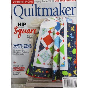 Puede incluir: Una copia de la revista Quiltmaker con un edredón colorido sobre una superficie blanca. El edredón presenta patrones geométricos rojos, azules, verdes y blancos. La portada de la revista tiene el texto "HIP to be Square" y "Meet the Quilting Cowboy."