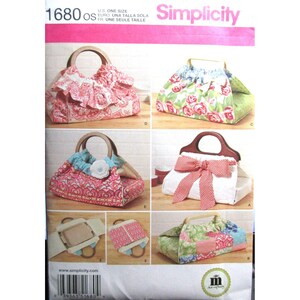 Puede incluir: Un sobre de patrón de costura Simplicity 1680 con ilustraciones de seis bolsos diferentes. Los bolsos muestran varios patrones de tela, incluidos estampados florales y geométricos, y cuentan con asas de madera, volantes, lazos y detalles de flores de tela.