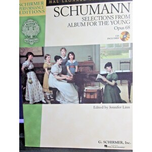 May include: A book cover featuring a painting of children playing music. The title is "Schumann Selections from Album for the Young Opus 68". A CD is included.