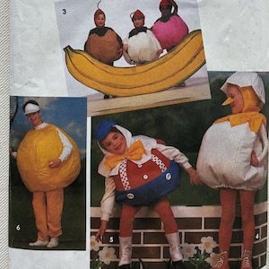 May include: A Simplicity sewing pattern envelope 7415, size A (SM-LG), featuring illustrations of various food-themed costumes. The images display outfits shaped like a banana, a lemon, a round egg, and a character with a red, white, and blue body.