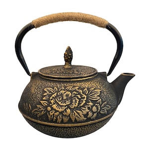May include: Black cast iron teapot with a gold floral design and a rope handle.