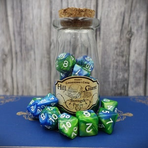 May include: A glass bottle with a cork stopper filled with blue and green swirl dice. The bottle has a label that reads "Hill Giant Strength Potion".