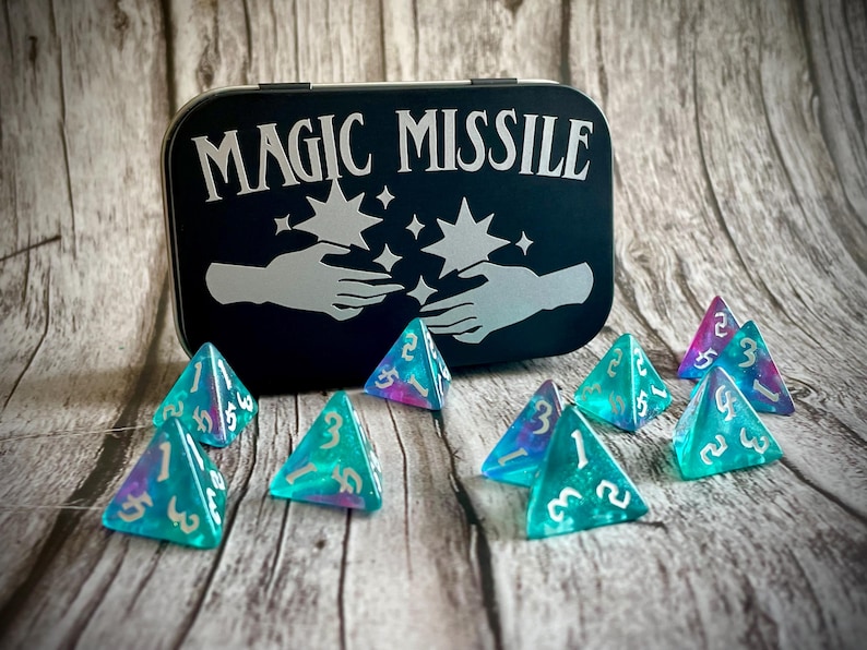 K&ouml;nnte beinhalten: Eine schwarze Metalldose mit der Aufschrift "Magic Missile". Die Dose ist ge&ouml;ffnet und enth&auml;lt acht schimmernde blaue und violette vierseitige W&uuml;rfel.