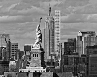 May include: A black and white photograph of the Statue of Liberty and the Empire State Building in New York City. The Statue of Liberty is in the foreground, and the Empire State Building is in the background. The sky is cloudy.