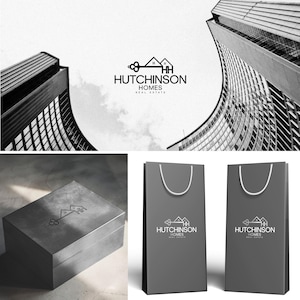 Hutchinson Homes Real Estate custom logo design — key and house icon with HH monogram, shown on luxury packaging, gift box, and branded bags. Professional real estate brand identity by 90Designs.