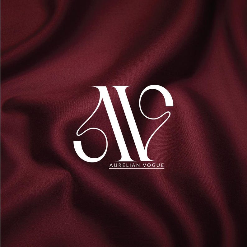 May include: White logo with the text "AURELIAN VOGUE" on a deep burgundy fabric background. The logo features stylized letters, with the "A" and "V" intertwined. The fabric has a silky, flowing texture.