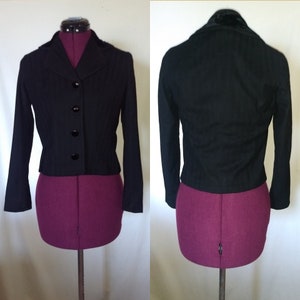 May include: A black cropped jacket with a velvet collar and four black buttons down the front.
